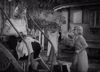 Movie still from “Freaks” (1932), directed by Tod Browning – A woman sitting on a chair next to a girl; Wide shot, High angle