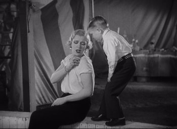 Movie still from “Freaks” (1932), directed by Tod Browning – A woman sitting on the ground next to a young boy; Medium shot, Low angle