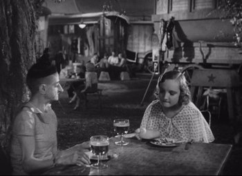 Movie still from “Freaks” (1932), directed by Tod Browning – A man and a woman sitting at a table with a plate of food; Medium shot, High angle