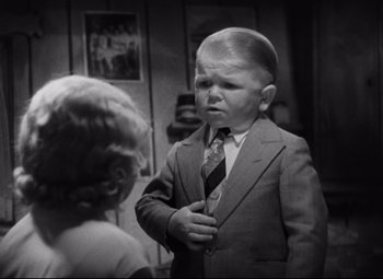 Movie still from “Freaks” (1932), directed by Tod Browning – A little boy wearing a suit and a tie; Medium shot, High angle