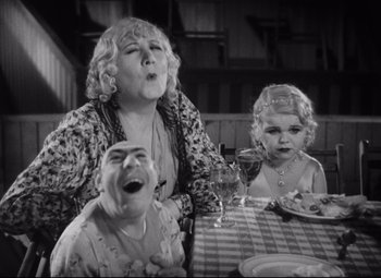 Movie still from “Freaks” (1932), directed by Tod Browning – An older woman and two young girls sitting at a dinner table; Medium shot, High angle