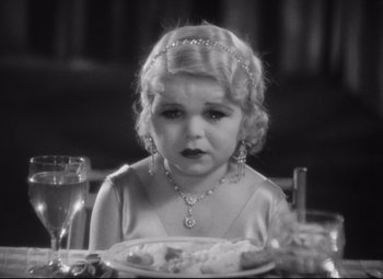 Movie still from “Freaks” (1932), directed by Tod Browning – A little girl sitting at a dinner table; Close Up shot, High angle