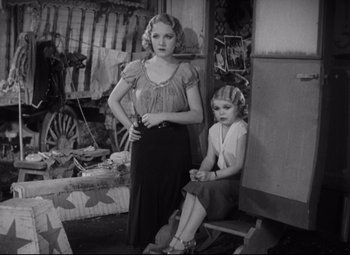 Movie still from “Freaks” (1932), directed by Tod Browning – A woman standing next to a little girl in a room; Medium shot, High angle