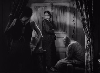 Movie still from “Freaks” (1932), directed by Tod Browning – A black and white photo of a woman and two men; Medium shot, Over the shoulder angle