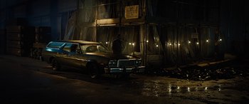 Movie still from “Free Fire” (2016), directed by Ben Wheatley – A car parked in front of a building at night; Wide shot, Low angle