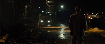 Movie still from “Free Fire” (2016), directed by Ben Wheatley – A man standing on the side of a road at night; Medium shot, Over the shoulder angle