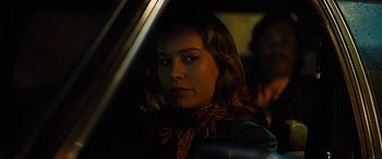 Movie still from “Free Fire” (2016), directed by Ben Wheatley – A woman sitting in the driver's seat of a car at night; Close Up shot, Over the shoulder angle