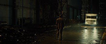 Movie still from “Free Fire” (2016), directed by Ben Wheatley – A man walking in the dark on a wet street; Wide shot, Low angle
