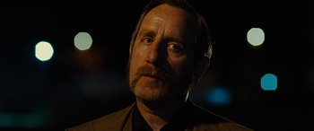 Movie still from “Free Fire” (2016), directed by Ben Wheatley – A person with a beard and mustache; Close Up shot, Over the shoulder angle