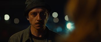 Movie still from “Free Fire” (2016), directed by Ben Wheatley – A person wearing a hat; Close Up shot, Over the shoulder angle