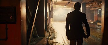 Movie still from “Free Fire” (2016), directed by Ben Wheatley – A man in a suit walking down a hallway; Wide shot, Low angle