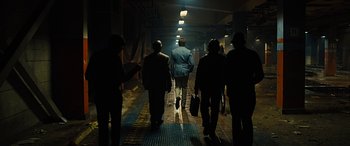 Movie still from “Free Fire” (2016), directed by Ben Wheatley – A group of people walking down a hallway at night; Wide shot, Low angle