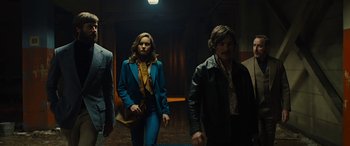 Movie still from “Free Fire” (2016), directed by Ben Wheatley – A man and a woman walking down a hall way; Medium shot, Low angle