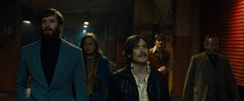 Movie still from “Free Fire” (2016), directed by Ben Wheatley – A group of people standing around in a room; Medium shot, Low angle