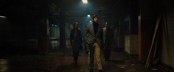 Movie still from “Free Fire” (2016), directed by Ben Wheatley – A group of people walking down a dark hallway; Wide shot, Low angle