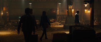 Movie still from “Free Fire” (2016), directed by Ben Wheatley – Two women walking in a room with rubble scattered around it; Wide shot, Over the shoulder angle