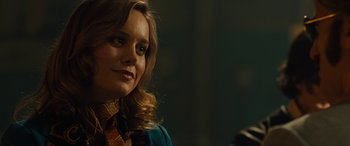 Movie still from “Free Fire” (2016), directed by Ben Wheatley – A person wearing a blue shirt; Close Up shot, Over the shoulder angle