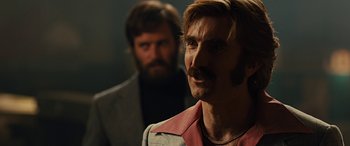 Movie still from “Free Fire” (2016), directed by Ben Wheatley – A man with a beard and a mustache; Close Up shot, Over the shoulder angle