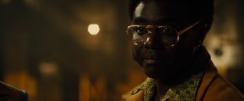 Movie still from “Free Fire” (2016), directed by Ben Wheatley – A person wearing glasses; Close Up shot, Over the shoulder angle