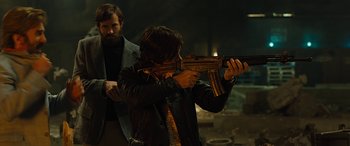 Movie still from “Free Fire” (2016), directed by Ben Wheatley – A man holding a gun while standing next to another man; Medium shot, Low angle