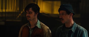 Movie still from “Free Fire” (2016), directed by Ben Wheatley – Two men standing next to each other in front of a building; Close Up shot, Low angle