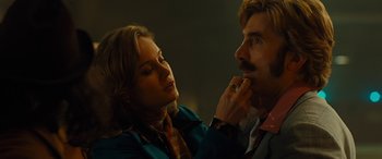 Movie still from “Free Fire” (2016), directed by Ben Wheatley – A woman putting lipstick on a man's face; Close Up shot, Low angle