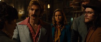 Movie still from “Free Fire” (2016), directed by Ben Wheatley – A man and a woman standing next to each other; Medium shot, Over the shoulder angle
