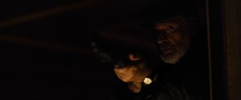 Movie still from “Free Fire” (2016), directed by Ben Wheatley – A man holding a gun in a dark room; Close Up shot, Low angle