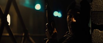 Movie still from “Free Fire” (2016), directed by Ben Wheatley – A man holding a gun while sitting in a room; Close Up shot, Low angle