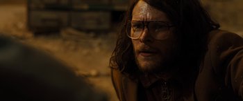 Movie still from “Free Fire” (2016), directed by Ben Wheatley – A person wearing glasses; Close Up shot, Over the shoulder angle