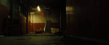 Movie still from “Free Fire” (2016), directed by Ben Wheatley – An empty room in a building with a red light above it; Wide shot, Low angle
