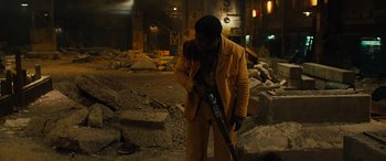 Movie still from “Free Fire” (2016), directed by Ben Wheatley – A man holding a gun in a building with rubble in front of him; Medium shot, High angle