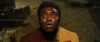 Movie still from “Free Fire” (2016), directed by Ben Wheatley – A person wearing a jacket with mud on it; Close Up shot, High angle