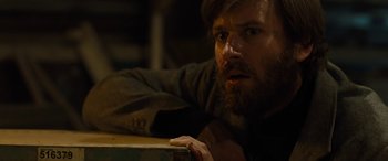 Movie still from “Free Fire” (2016), directed by Ben Wheatley – A man with a long beard and a beard on his face; Close Up shot, Over the shoulder angle