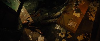 Movie still from “Free Fire” (2016), directed by Ben Wheatley – A man is lying on the ground in the dark; Medium shot, Overhead angle