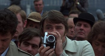 Movie still from “Frenzy” (1972), directed by Alfred Hitchcock – A man taking a picture with a camera in front of a crowd; Close Up shot, Low angle