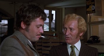 Movie still from “Frenzy” (1972), directed by Alfred Hitchcock – Two men in suits talking to each other; Close Up shot, Low angle