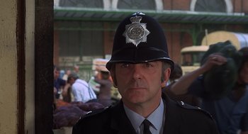 Movie still from “Frenzy” (1972), directed by Alfred Hitchcock – A man wearing a police uniform and a hat; Close Up shot, Low angle