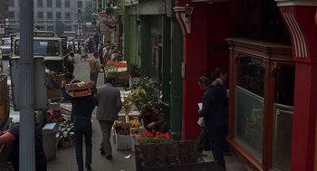 Movie still from “Frenzy” (1972), directed by Alfred Hitchcock – A group of people walking down a street near a flower shop; Extreme Wide shot, High angle