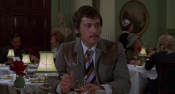 Movie still from “Frenzy” (1972), directed by Alfred Hitchcock – A man sitting at a table with a glass of wine; Medium shot, Over the shoulder angle
