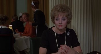 Movie still from “Frenzy” (1972), directed by Alfred Hitchcock – A woman sitting in front of a table with other people; Close Up shot, Over the shoulder angle