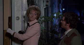 Movie still from “Frenzy” (1972), directed by Alfred Hitchcock – A woman standing next to a man in a pink jacket; Medium shot, Over the shoulder angle