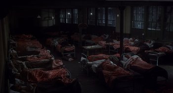 Movie still from “Frenzy” (1972), directed by Alfred Hitchcock – A room filled with lots of beds covered in blankets; Wide shot, High angle