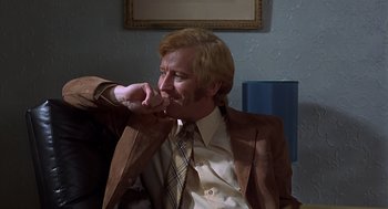 Movie still from “Frenzy” (1972), directed by Alfred Hitchcock – A man in a suit and tie sitting in front of a mirror; Close Up shot, Low angle