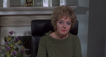Movie still from “Frenzy” (1972), directed by Alfred Hitchcock – A woman sitting in a chair in front of a fire place; Close Up shot, Over the shoulder angle