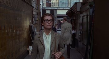 Movie still from “Frenzy” (1972), directed by Alfred Hitchcock – A woman with a purse standing on a city street; Medium shot, Low angle