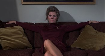 Movie still from “Frenzy” (1972), directed by Alfred Hitchcock – A woman sitting on a couch with her arms outstretched; Medium shot, Low angle