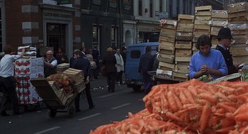 Movie still from “Frenzy” (1972), directed by Alfred Hitchcock – A street scene with people and carts full of food; Wide shot, High angle