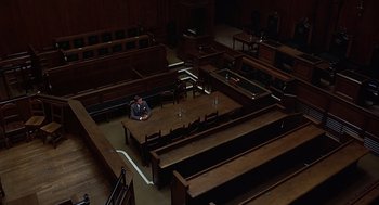 Movie still from “Frenzy” (1972), directed by Alfred Hitchcock – A man sitting at a table in a court room; Extreme Wide shot, High angle