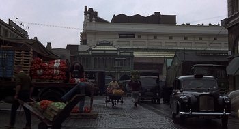 Movie still from “Frenzy” (1972), directed by Alfred Hitchcock – A street scene with people and cars on the side of the road; Wide shot, High angle